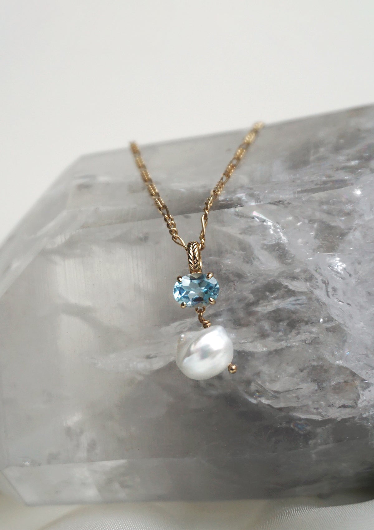 Gold plated necklace pendant with a freshwater pearl and blue topaz gemstone from carré on a figaro chain