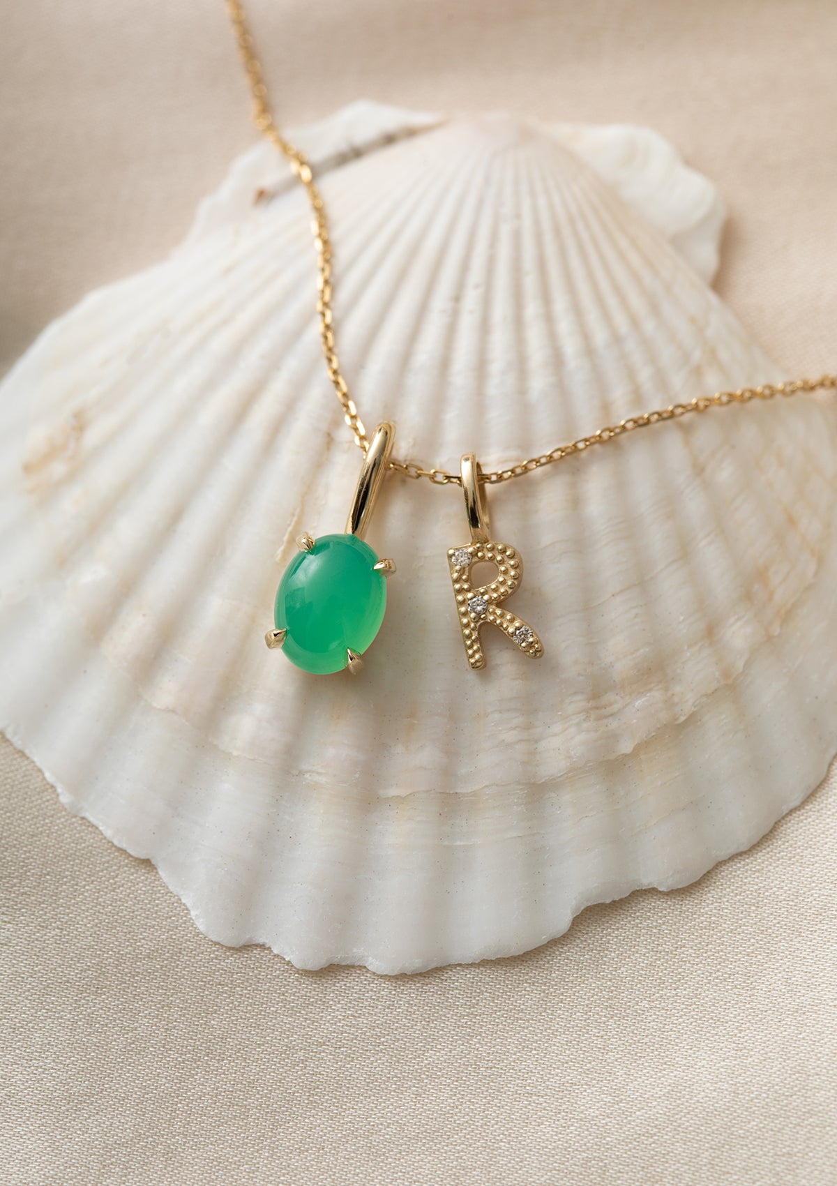 solid gold necklace with pendants from carré. The green pendant is with a chrysoprase gemstone, and a letter pendant with diamonds with the letter r