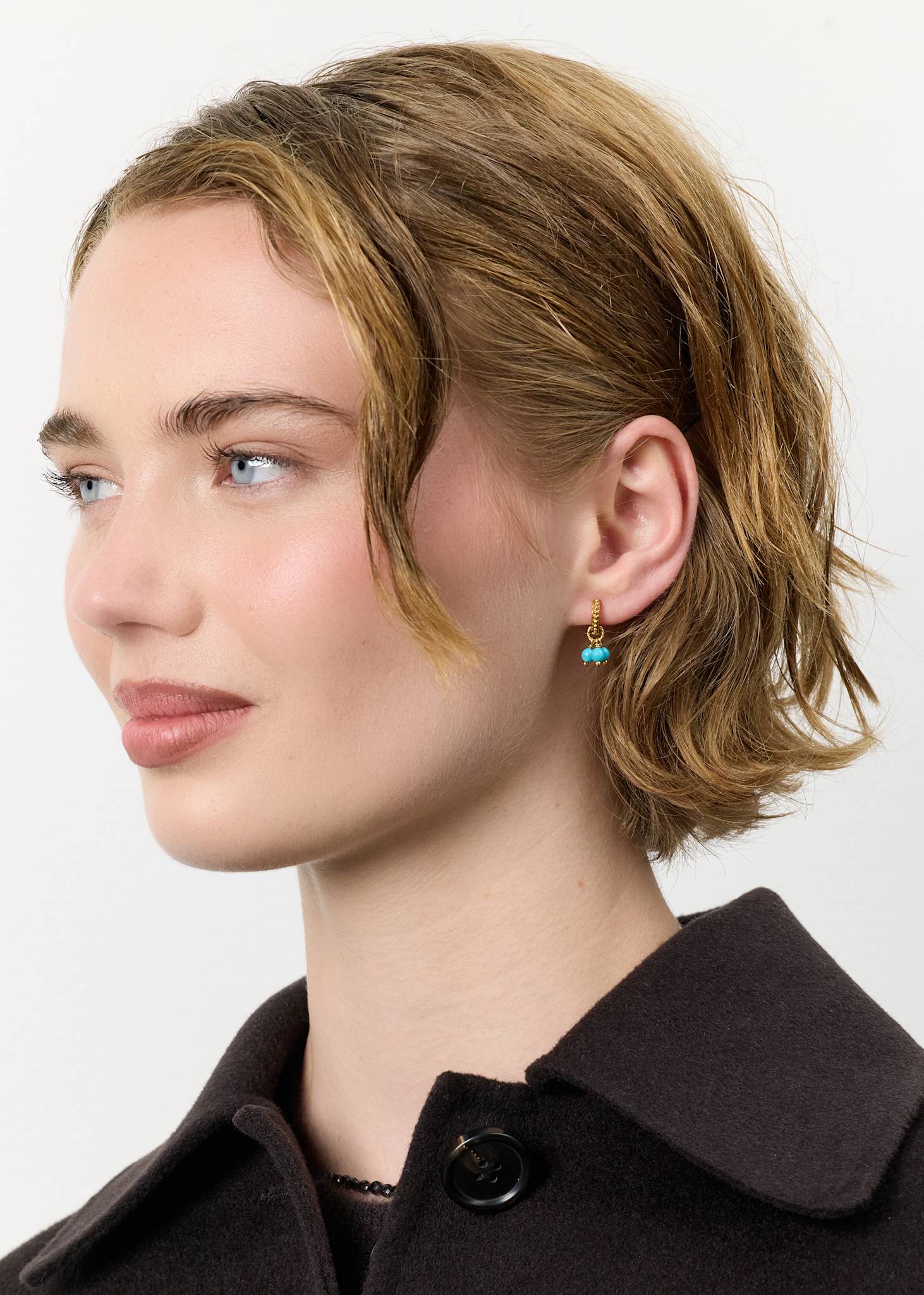 Ung kvinde med hoop øreringe i guldbelagt sølv fra carré jewellery sat med tre blå turkis ædelsten