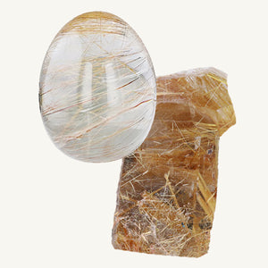 A cabochon-cut golden rutile quartz and a raw rutilated quartz gemstone on a beige background