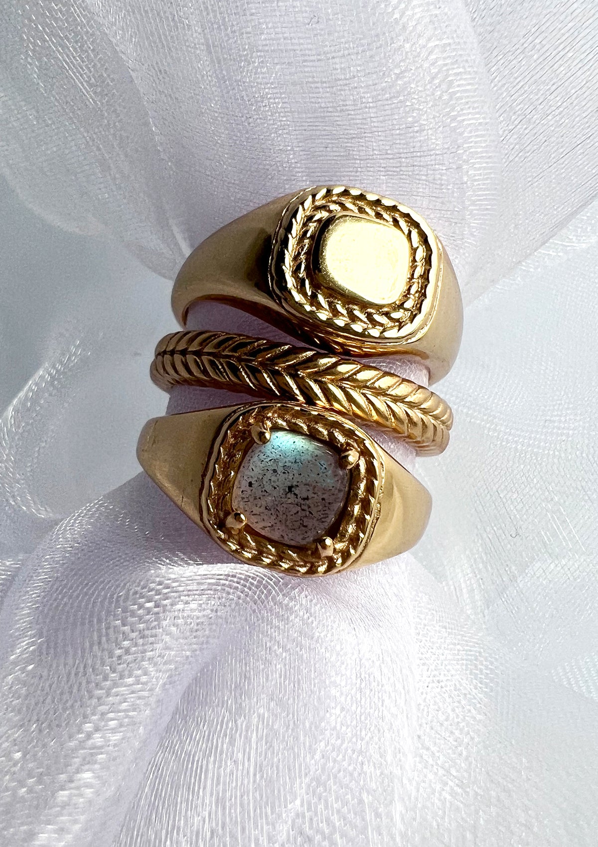 Three gold plated rings from carré. The top is a signét ring, the middle is a fishbone pattern ring, and the bottom one a signét ring with labradorite gemstone