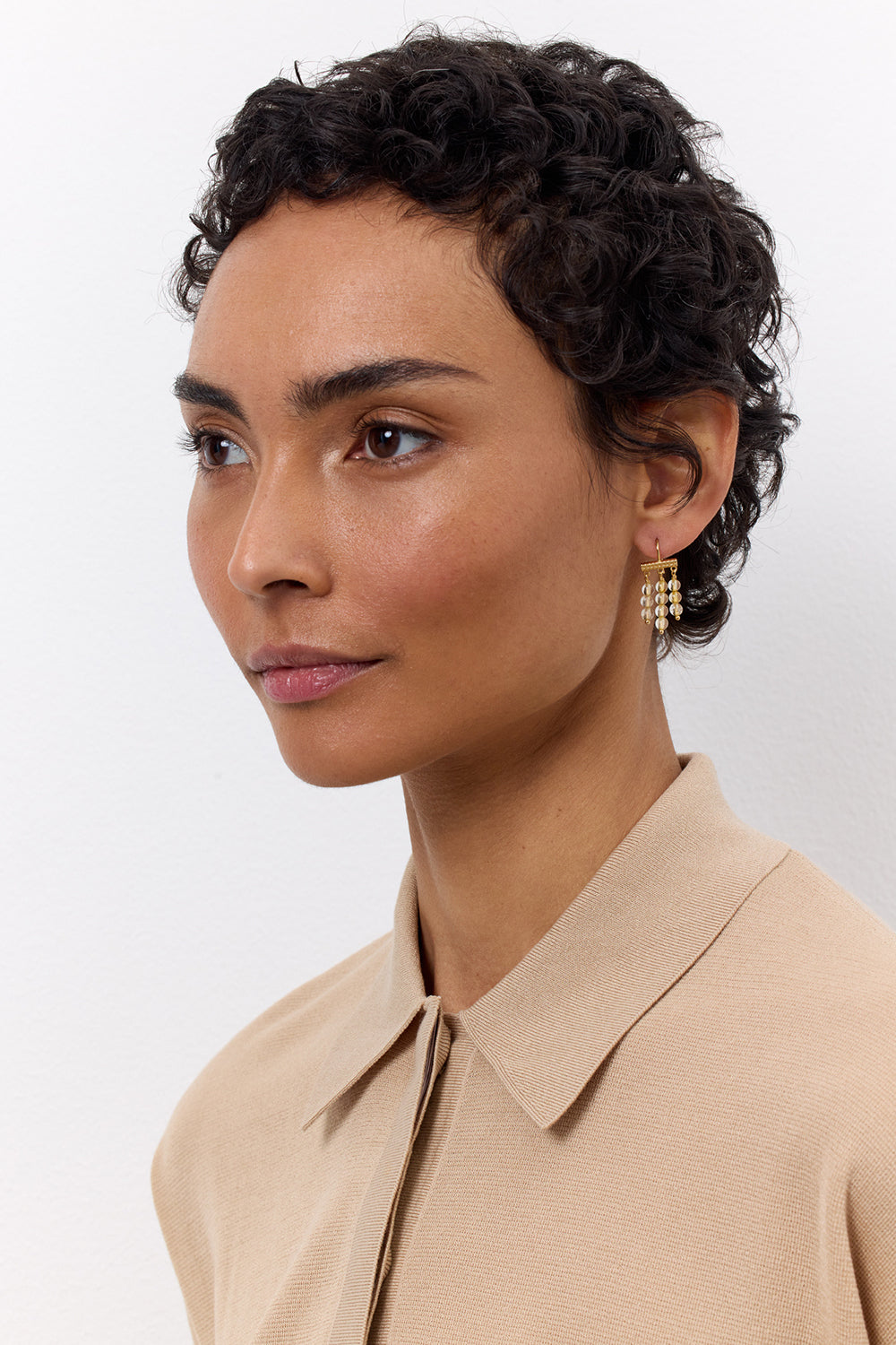 Woman wearing long gold plated earrings from Carré. The earrings are set with golden rutile quartz gemstones,