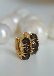 Small gold plated creole style hoops with dark stones from carré. The dark stones are brown smokey quartz stones