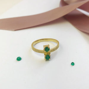 a solid gold ring from carré set with two emeralds