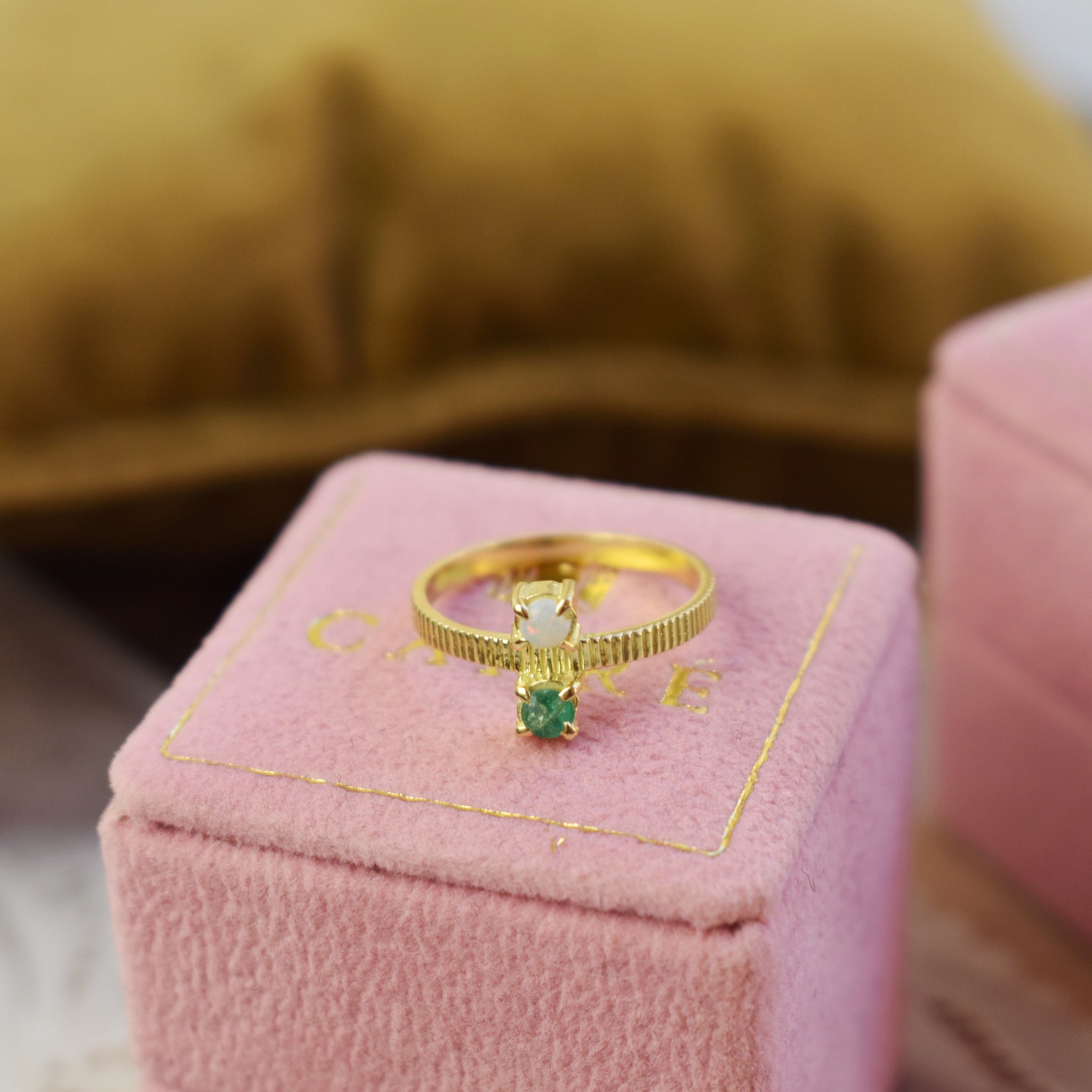 an 18karat gold ring from carré with emerald and opal on a pink jewellery box