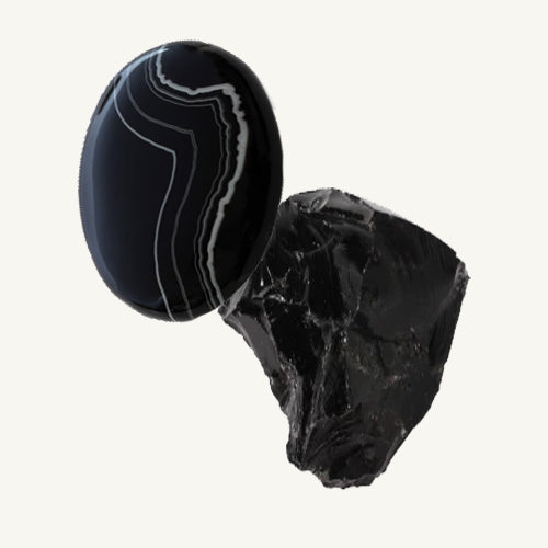 A cabochon-cut black agate and a raw black agate gemstone on a beige background