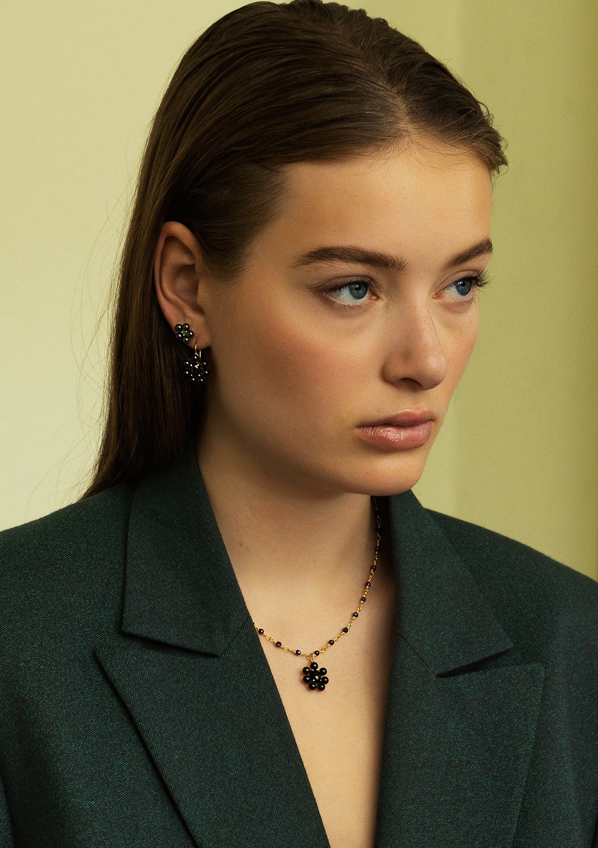 Woman with black agate jewellery from carré. She wears a necklace with a big Blackberry floral shaped pendant with black agate and flower earrings with green and black agate