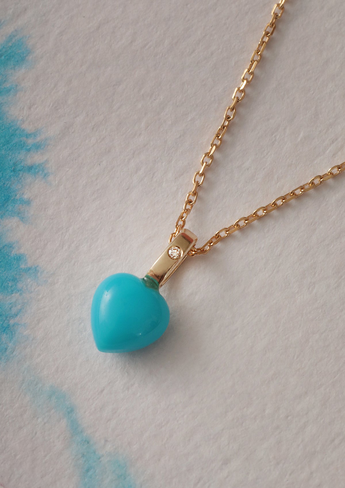 a solid gold heart pendant for necklaces from carré. The pendant has a heart shaped turquoise gemstone and a small diamond