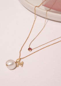 gold necklaces with pendants from carré. A letter pendant with the letter M and diamonds, a freshwater pearl pendant and a pink tourmaline necklace