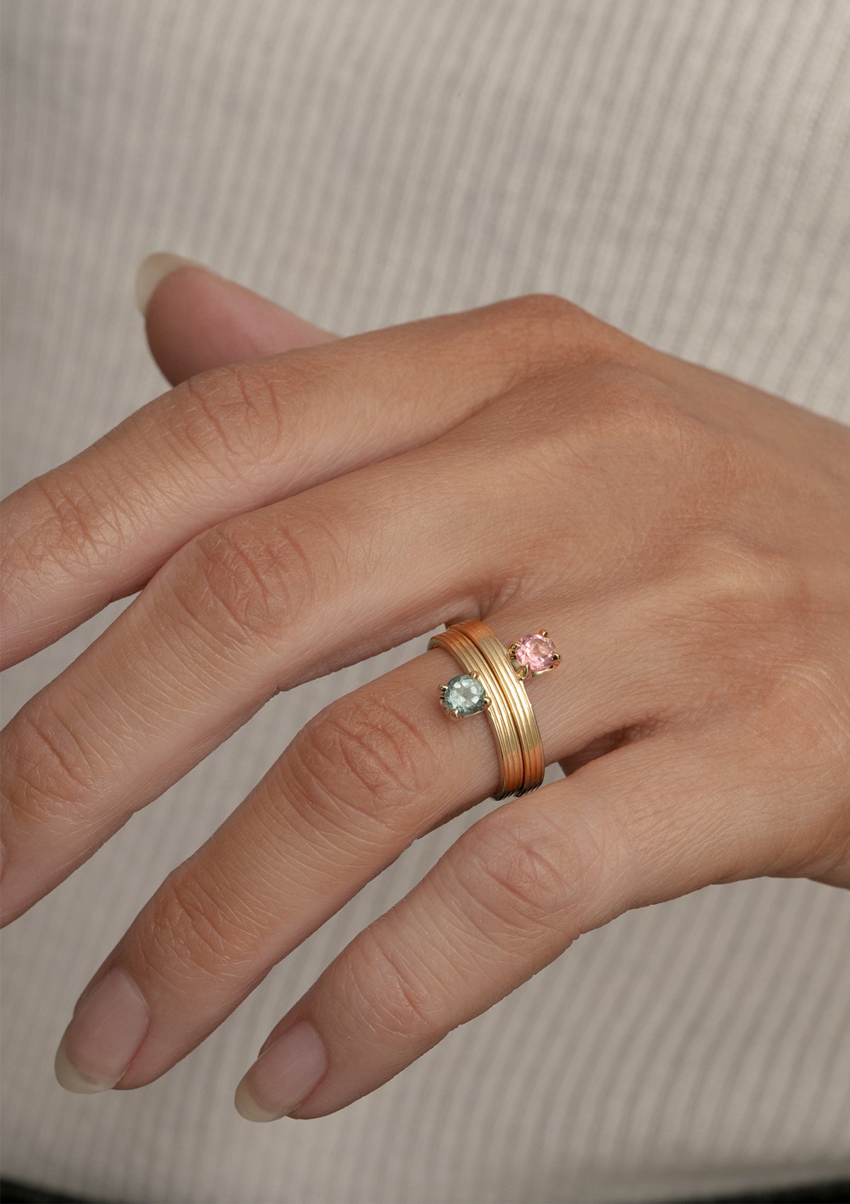 woman with two solid gold rings from carré. The rings are set with a pink tourmaline and a green tourmaline